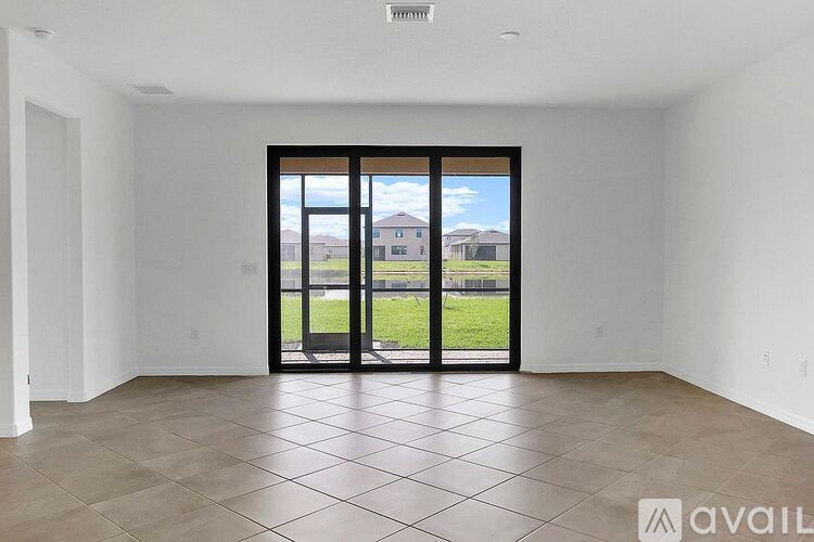 A spacious room with a large sliding door leading to a backyard.