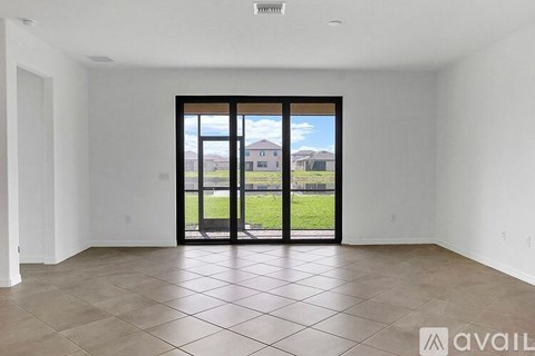 A spacious room with a large sliding door leading to a backyard.