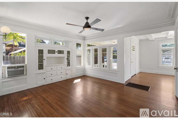 A spacious room with wood flooring and a ceiling fan.