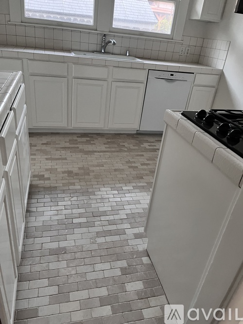 A kitchen with white cabinets and a tiled floor.