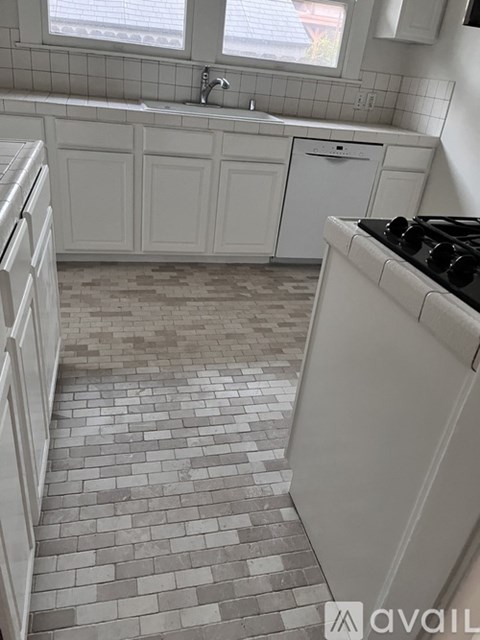 A kitchen with white cabinets and a tiled floor.