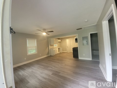 A spacious room with a ceiling fan and lighting fixture.