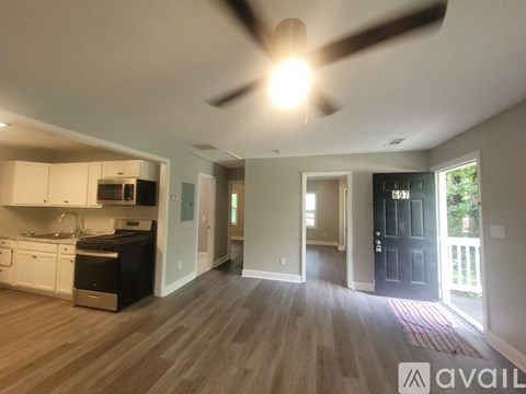 A well-lit kitchen with a ceiling fan and hardwood floors.