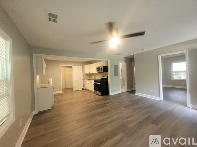 A spacious living room with a ceiling fan and hardwood flooring.