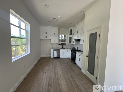 A kitchen with white cabinets and a wooden floor.