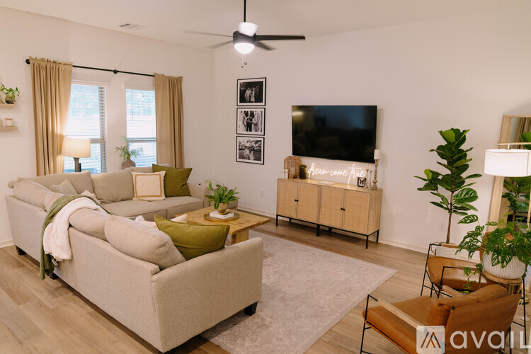 A living room with a beige sofa, a coffee table, a television, and a plant.