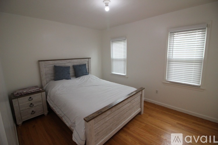 A bedroom with a bed, nightstand, and window with blinds.