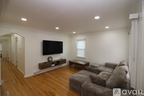 A living room with a brown couch and a flat screen TV mounted on the wall.