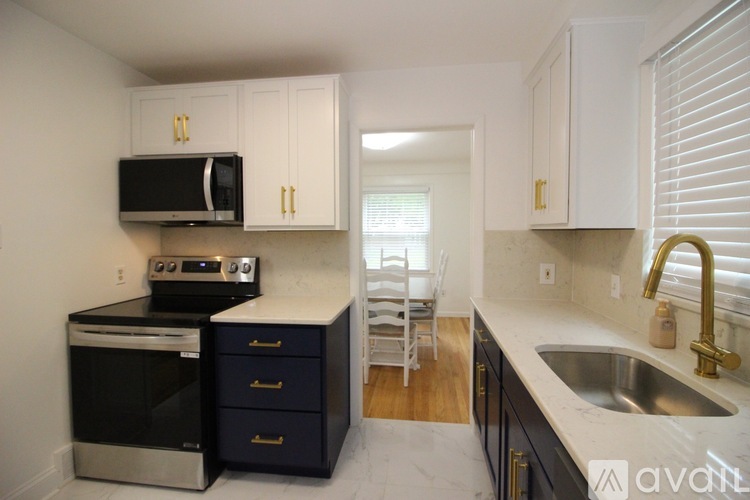 A kitchen with a black oven and microwave, a sink, and a dining table with chairs.