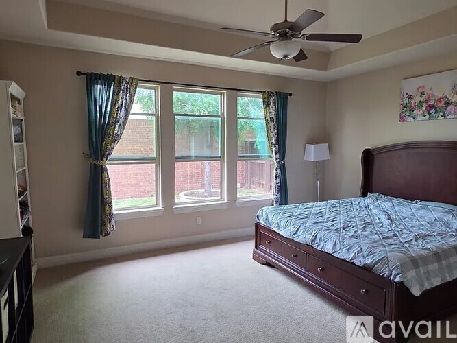 A bedroom with a bed, dresser, and window.