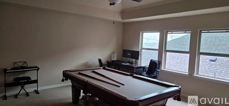 A pool table is in the middle of a room with a chair and a television.