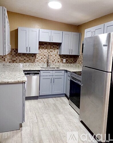 A kitchen with a refrigerator, sink, and cabinets.