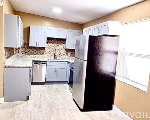 A kitchen with a black refrigerator and white cabinets.