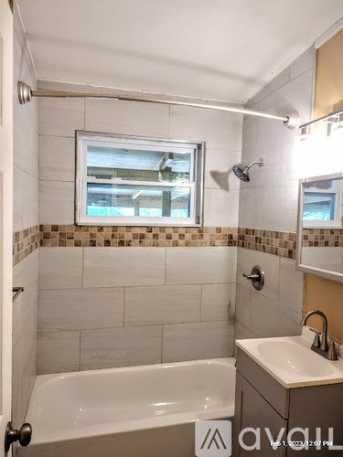 A bathroom with a white tub and sink, and a window with a view of a building.