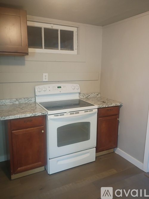 A white oven is on a granite countertop in a kitchen.