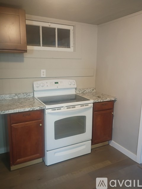 A white oven is on a granite countertop in a kitchen.