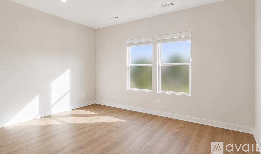 A room with wooden flooring and a window with a view of trees outside.