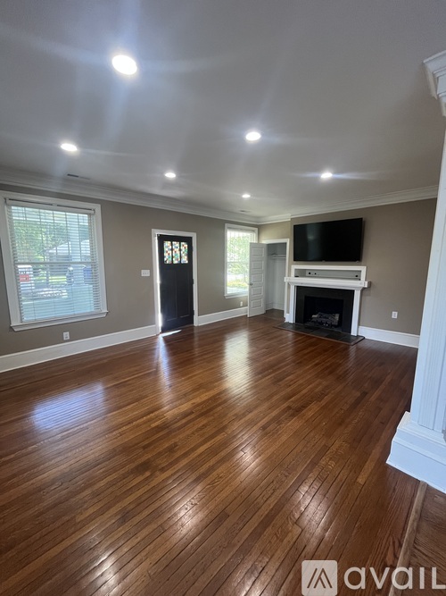 A spacious room with wooden flooring and a fireplace.
