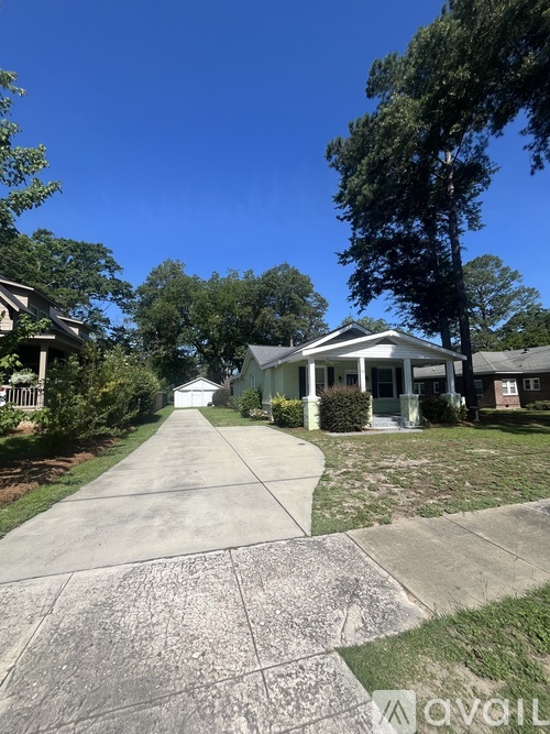 A white house with a porch and a driveway in front of it.