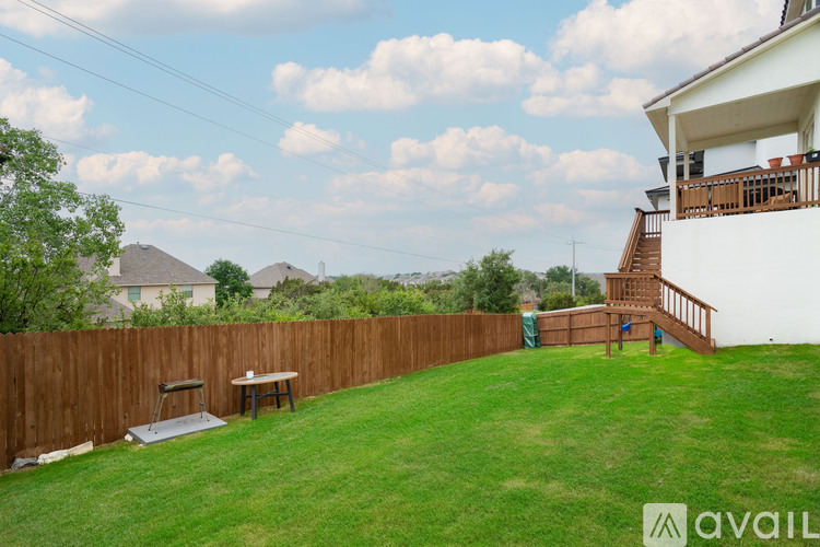 A backyard with a wooden fence, picnic table, and stairs leading to a deck.