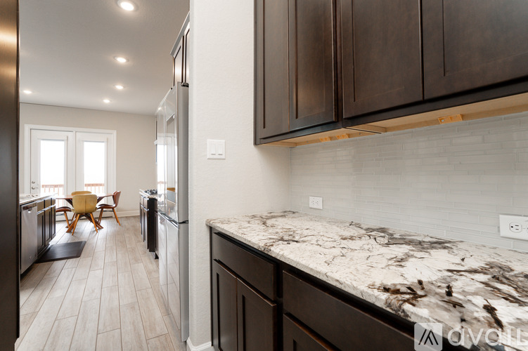 A kitchen with dark wood cabinets and a marble countertop.