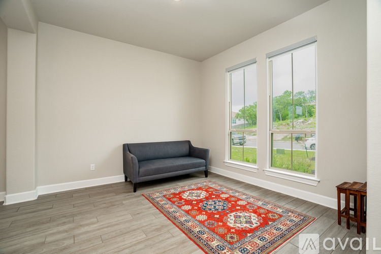 A living room with a grey couch, a small table, and a large window with a view of the outside.