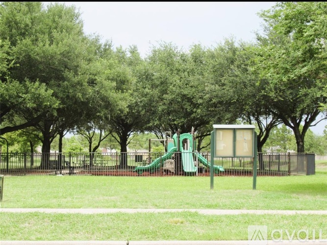 A playground with a green slide and a brown fence.