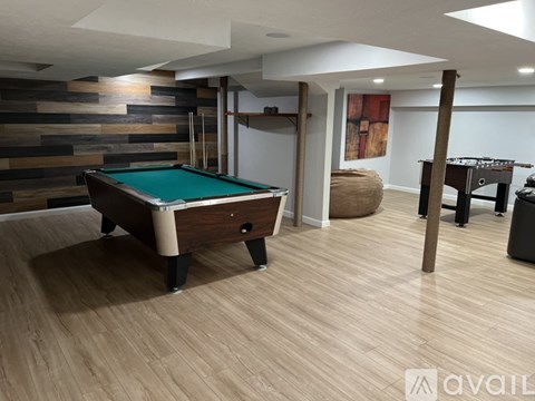 A pool table in a room with a wooden floor and a striped wall.