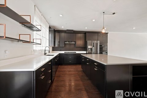 A modern kitchen with black cabinets and a white countertop.