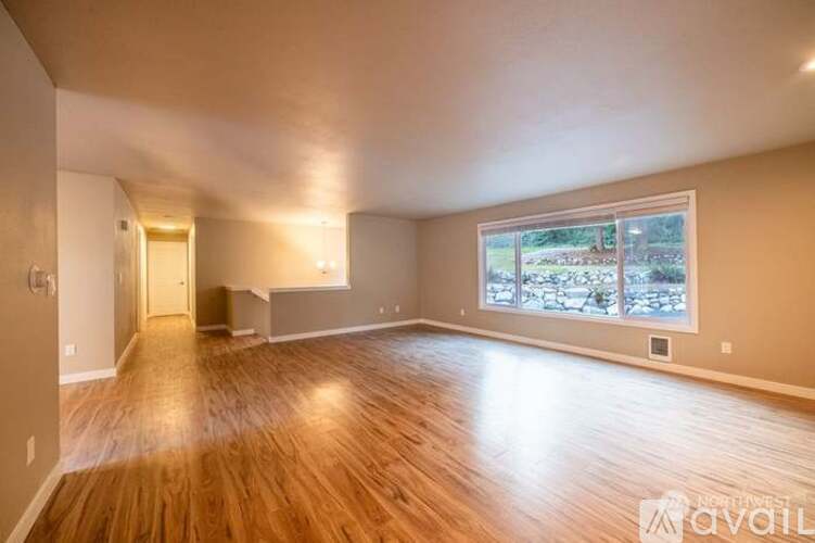 A spacious room with wooden floors and a large window.