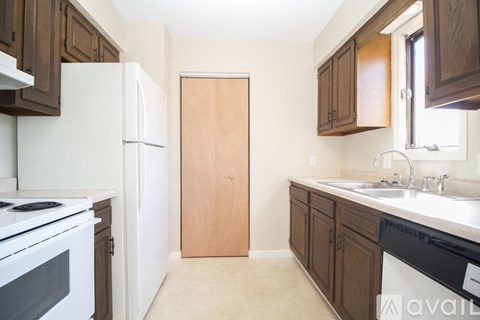 A kitchen with white appliances and wooden cabinets.