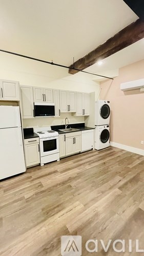 A kitchen with white appliances and wooden floors.