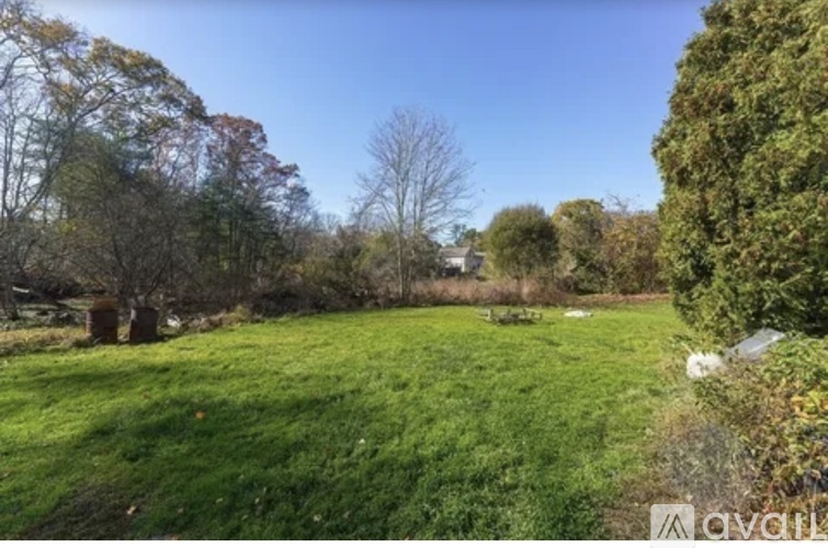 A grassy field with trees and a clear sky.