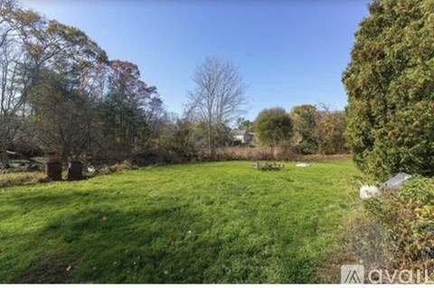 A grassy field with trees and a clear sky.