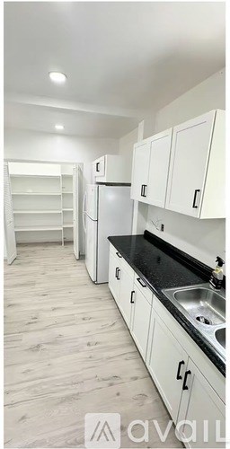 A kitchen with white cabinets and a black countertop.