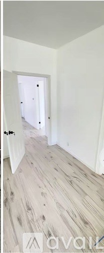 A hallway with wooden flooring and white walls.