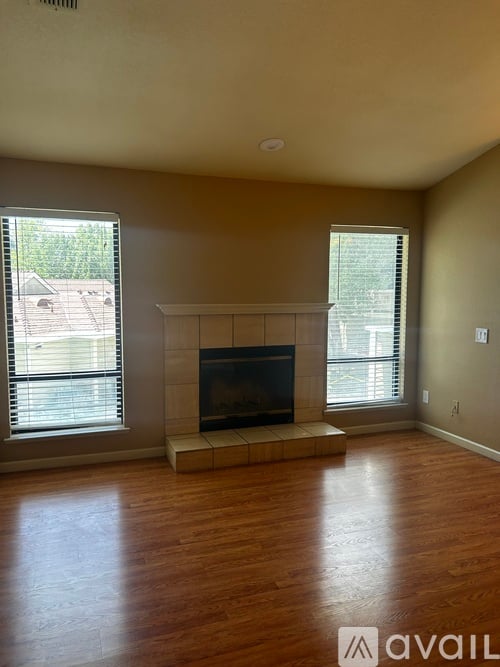 A living room with a fireplace and two windows.