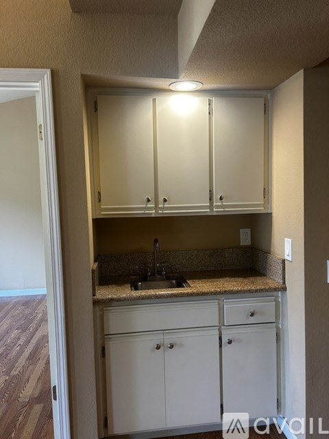 A kitchen with white cabinets and a granite countertop.
