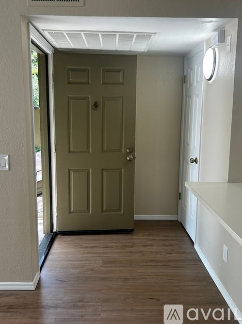 A hallway with a wooden floor and a white door.