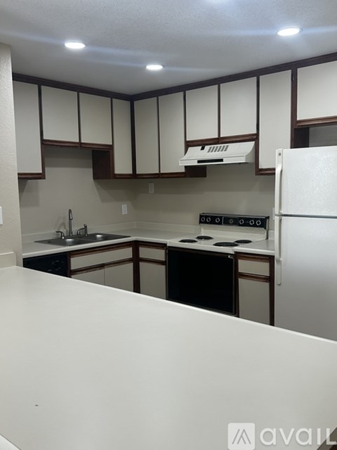 A kitchen with white appliances and brown cabinets.