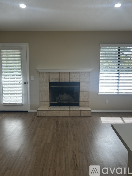A living room with a fireplace and wooden floors.