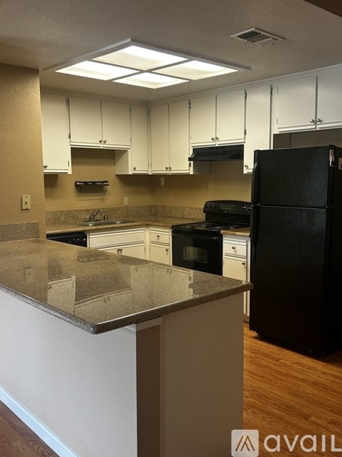 A kitchen with black appliances and white cabinets.