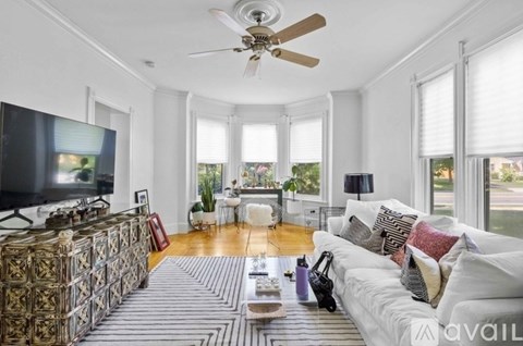 A living room with a white couch, a television, and a rug.