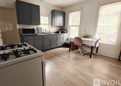 A kitchen with a white stove and a dining table with a pink chair.