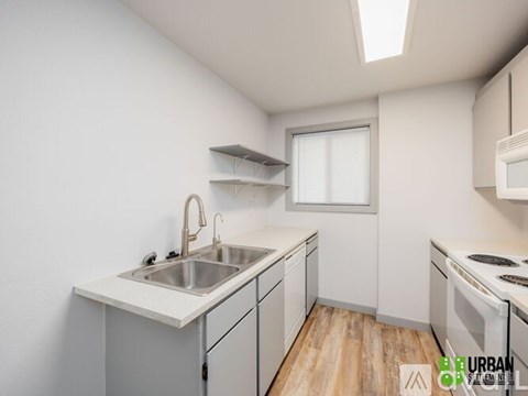 A kitchen with white cabinets and a wooden floor.