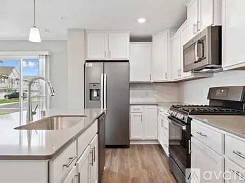 A kitchen with white cabinets and a stainless steel refrigerator.