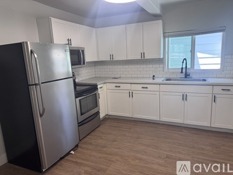 A kitchen with a black refrigerator and white cabinets.