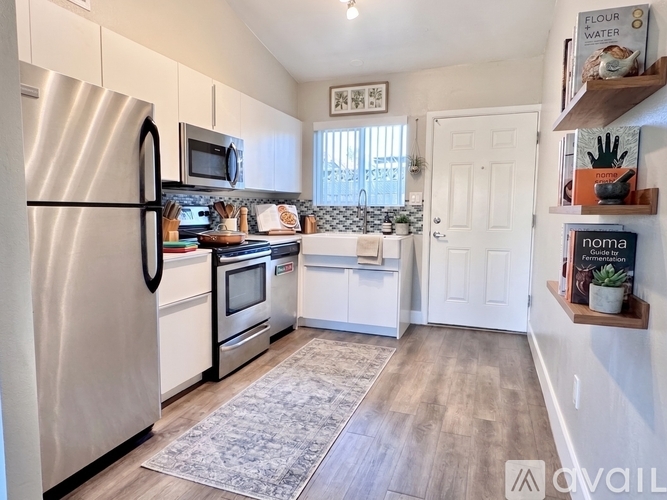 A kitchen with a refrigerator, microwave, oven, and sink.