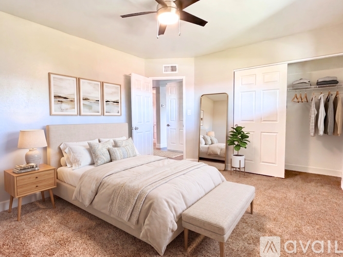 A bedroom with a large bed, a ceiling fan, and a clothing rack.