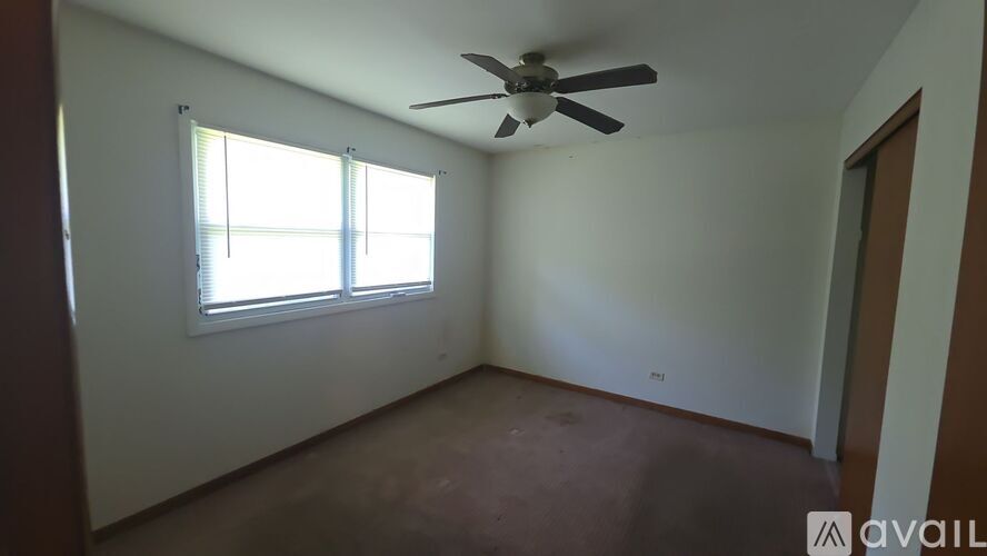 A room with a ceiling fan and a window.